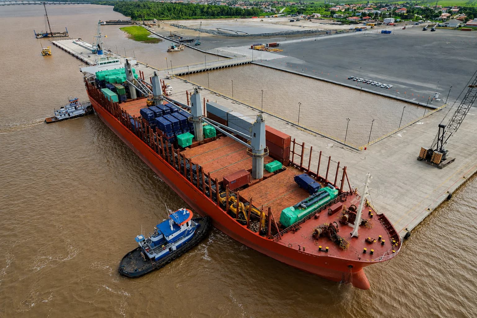A 169-metre handysize vessel assisted by tugboats during daytime berthing operations at Tristar Port of Guyana.