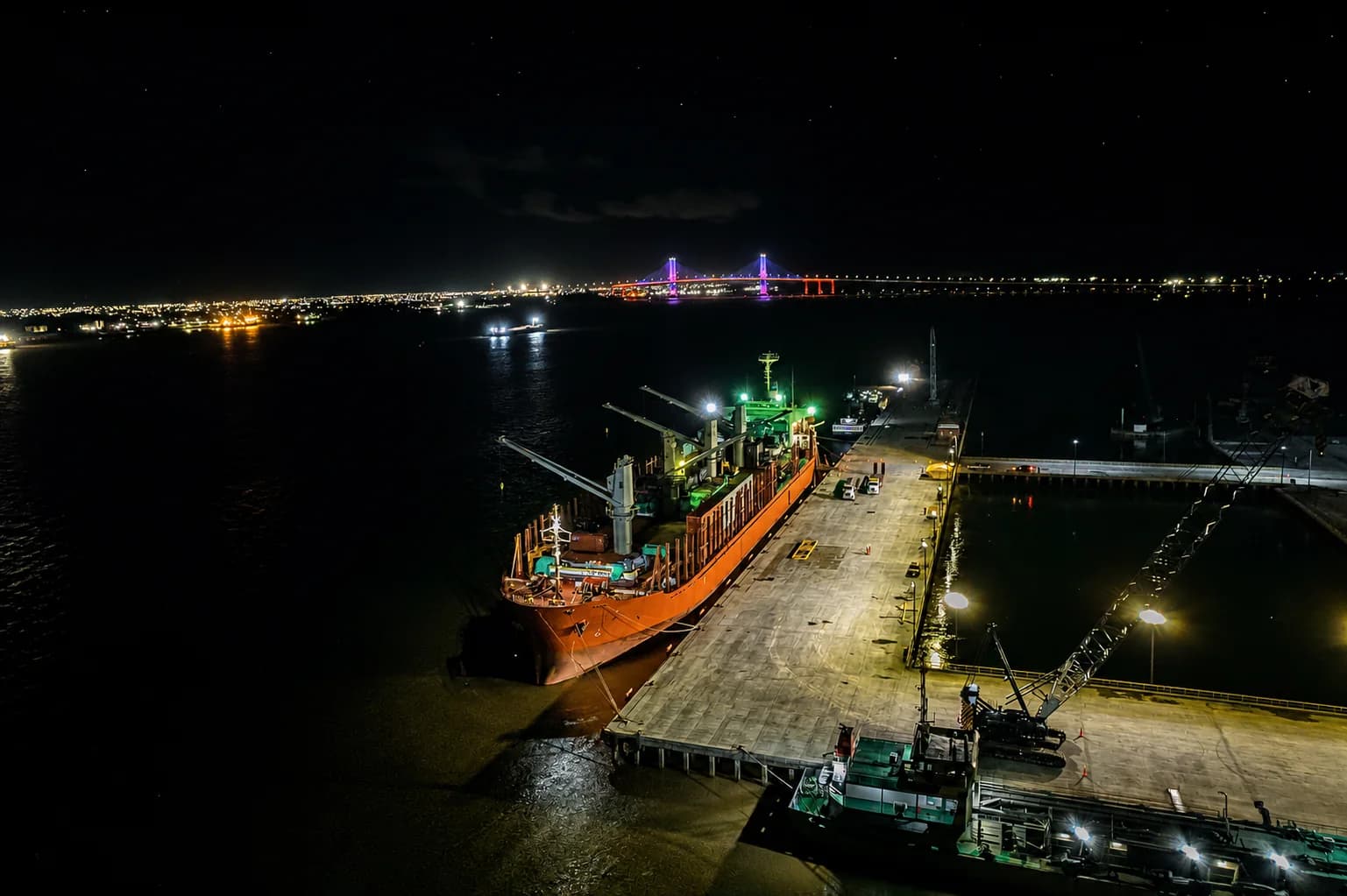 A handysize vessel alongside the illuminated Tristar quay during night-time cargo operations.